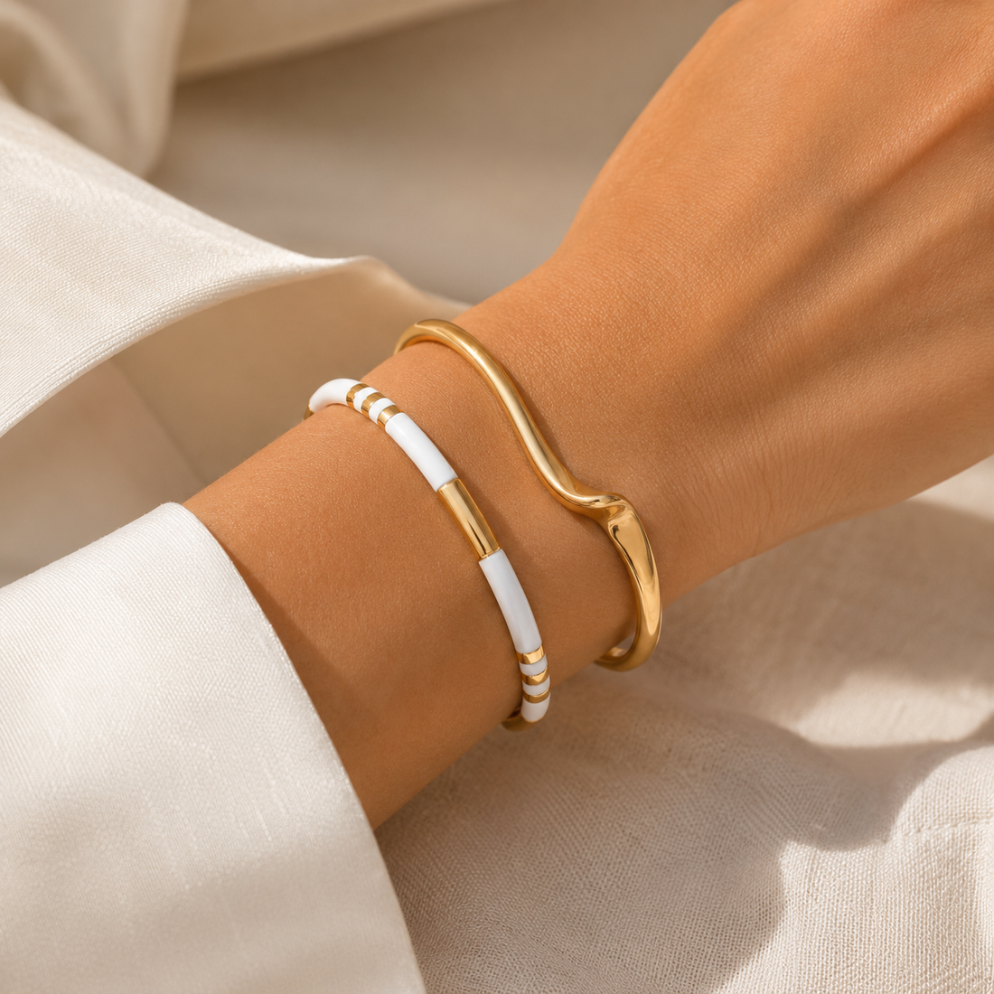Woman wearing the Alix sculptural gold cuff bracelet paired with the Riviera ivory bracelet in an elegant stacked jewelry look