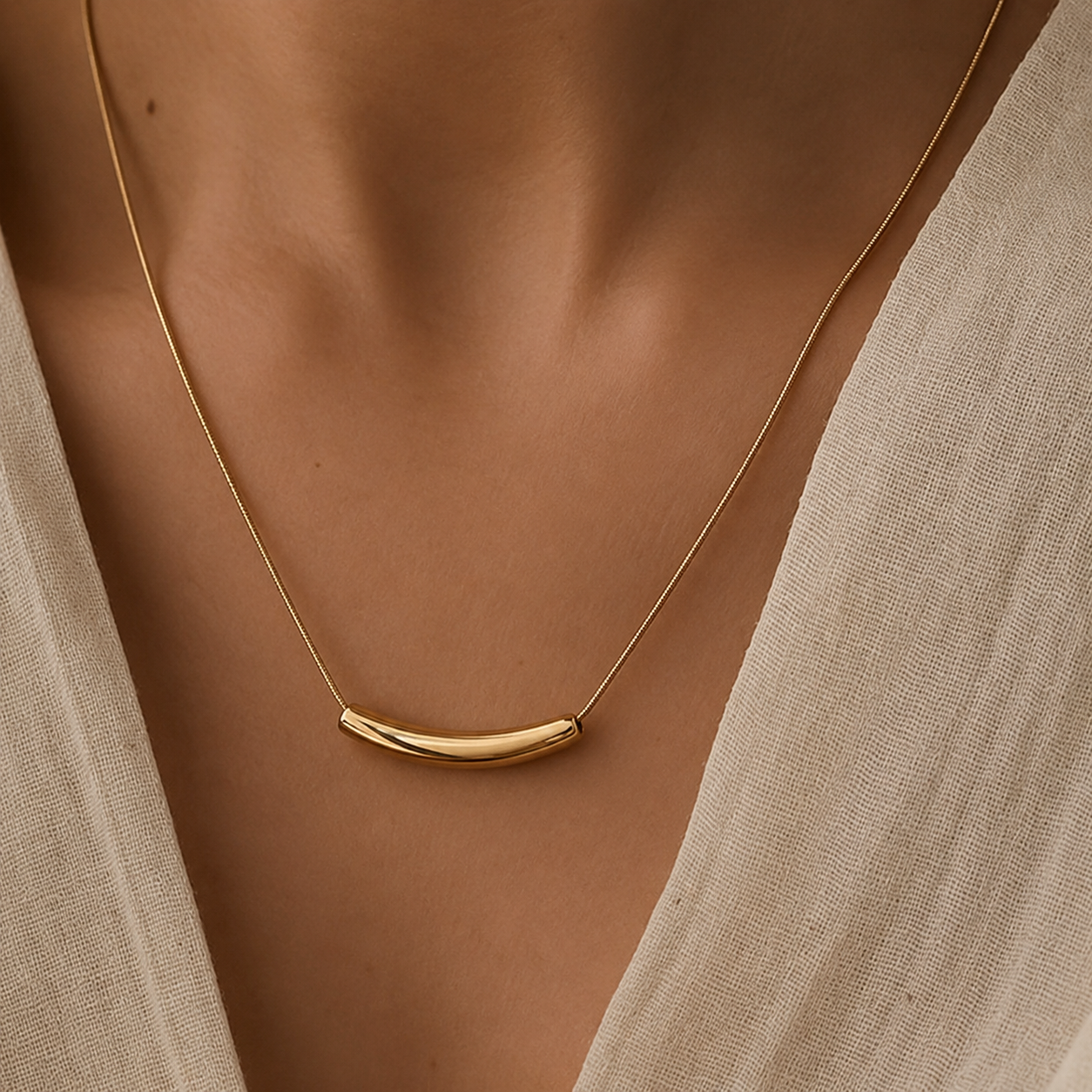 Woman wearing the Oria gold necklace as the anchor layer in a minimalist layered necklace look by Amelya Paris