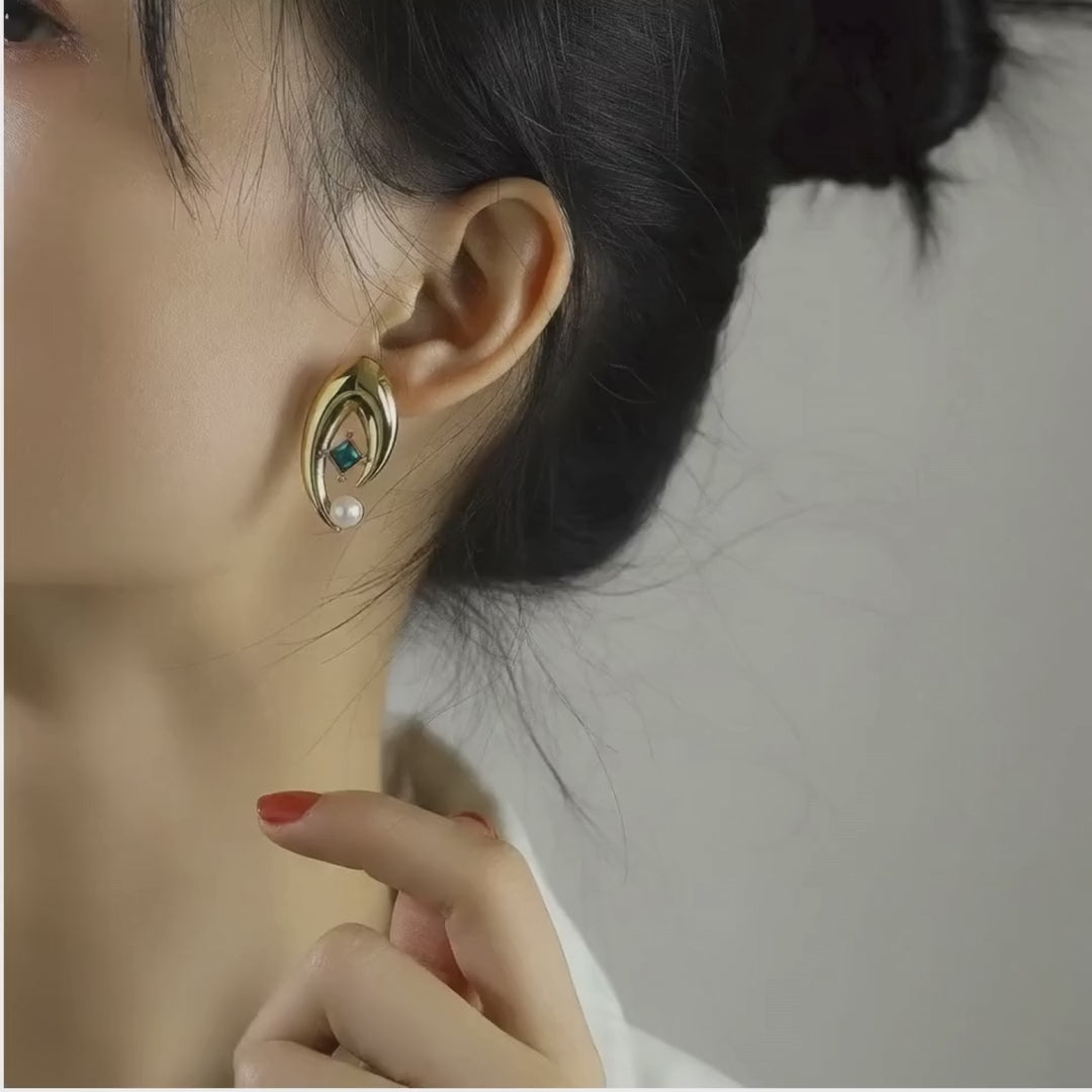 Model wearing Élysée gold-plated stainless steel earrings featuring a blue crystal and white pearl.